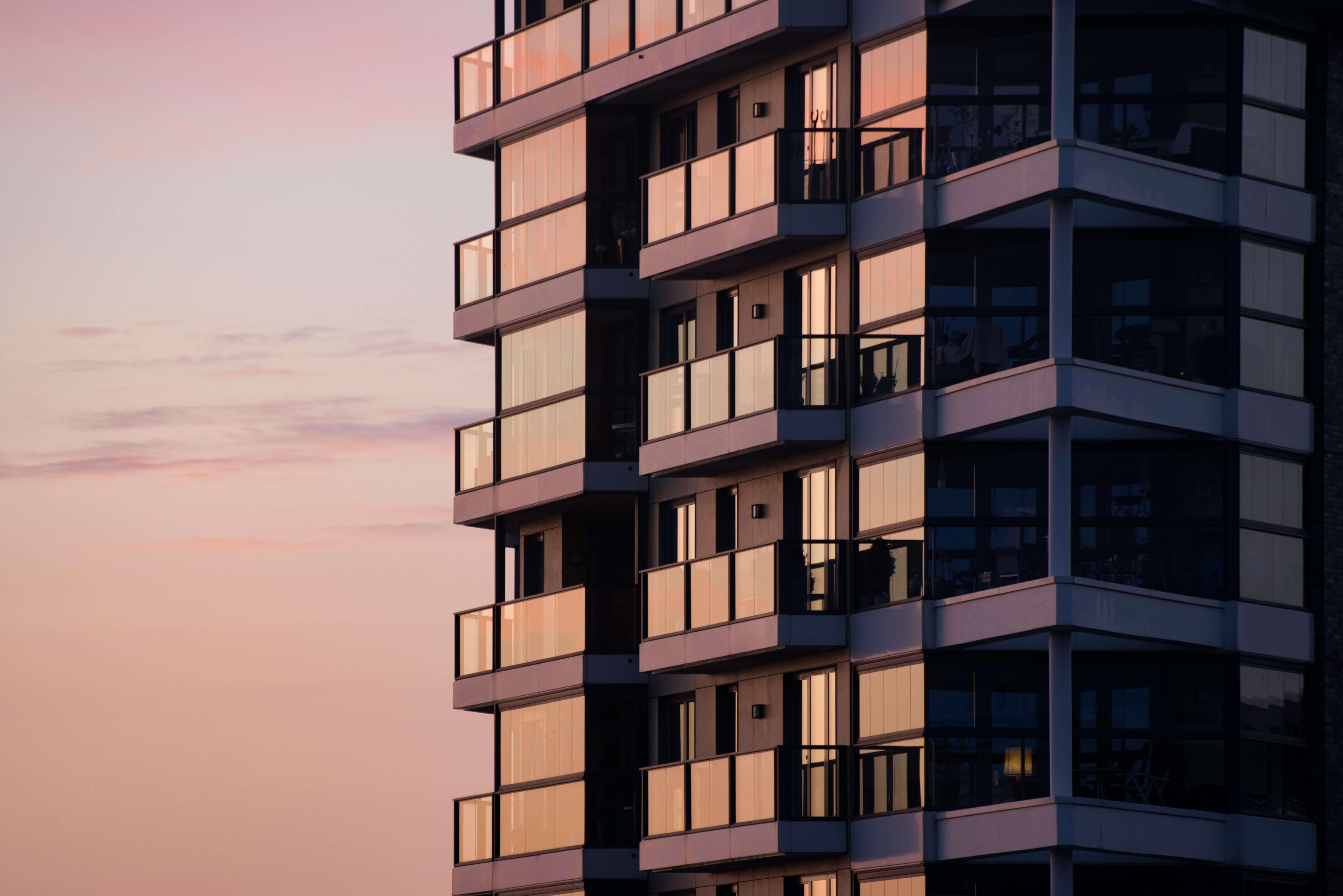 Modern residential condo building rendering at dusk with illuminated balconies